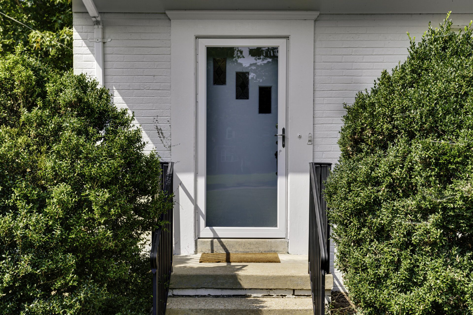 Front Door Entrance With Hedges And Concrete Steps Storm Doors